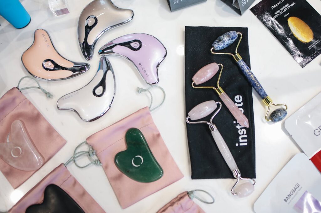 A collection of luxury facial rollers and beauty tools including jade and rose quartz items.