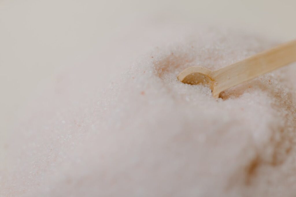 The Art of Drawing Readers In: Your attractive post title goes here A detailed close-up of pink Himalayan salt with a wooden spoon on a smooth surface.